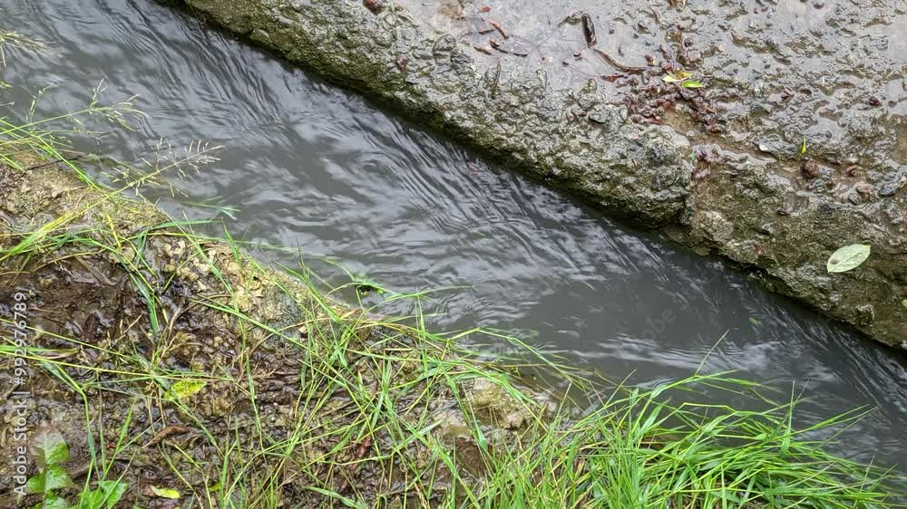 Concrete sidewalk drain with rainwater, during the rain top view. Concrete sidewalk drain with rainwater, during the rain top view.