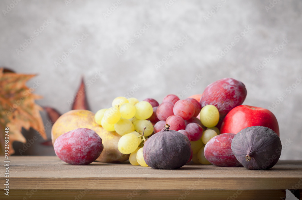 Autumn fruit on wooden table on grey light background. Grape, pears figs and plums. Autumn fruit on wooden table on grey light background. Grape, pears figs and plums.