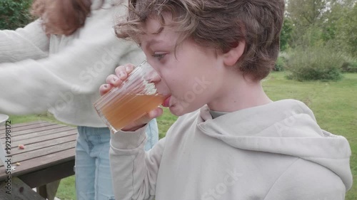 Close up of a boy's face drinking a glass of freshly squeezed apple juice