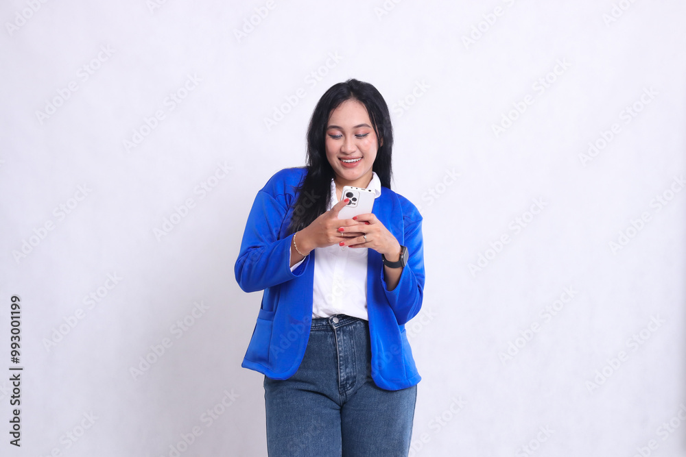 beautiful young office woman wearing blue formal suit standing wide smile candid both hands playing with smartphone. for technology content, lifestyle, mobile transactions beautiful young office woman wearing blue formal suit standing wide smile candid both hands playing with smartphone. for technology content, lifestyle, mobile transactions