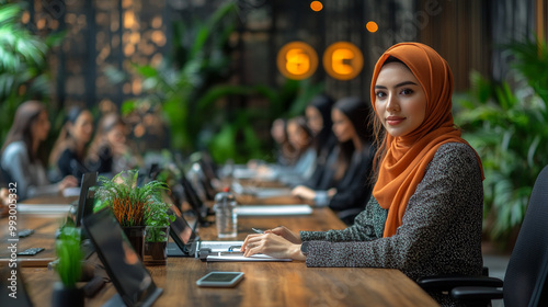 A confident woman in a hijab participates in a business meeting, showcasing diversity and teamwork in a modern office environment.