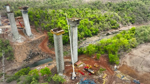 aerial view cranes and bridge foundation pillars on construction site. Aerial drone view of highway expressway road bridge under construction.