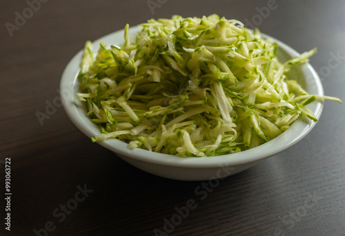  Shredded Zucchini in a White Bowl Close-Up on Dark Background