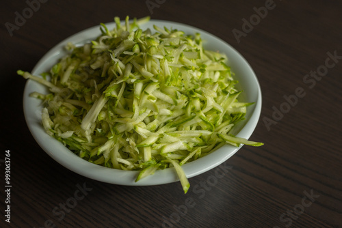  Shredded Zucchini in a White Bowl Close-Up on Dark Background