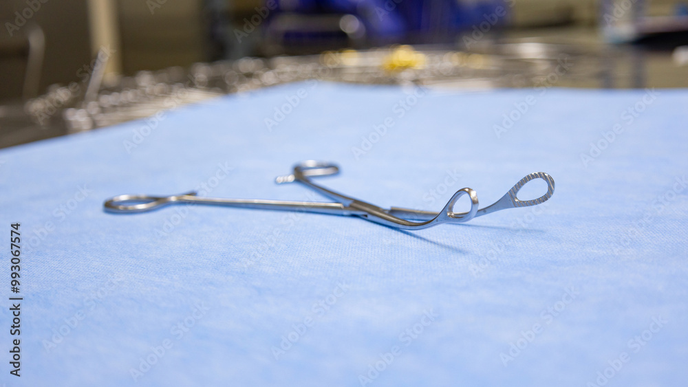 Fototapeta premium Stainless surgical sponge holding forceps placed on a blue background. Medical equipment used in surgery. Surgical instruments. Medical science and surgery concept.