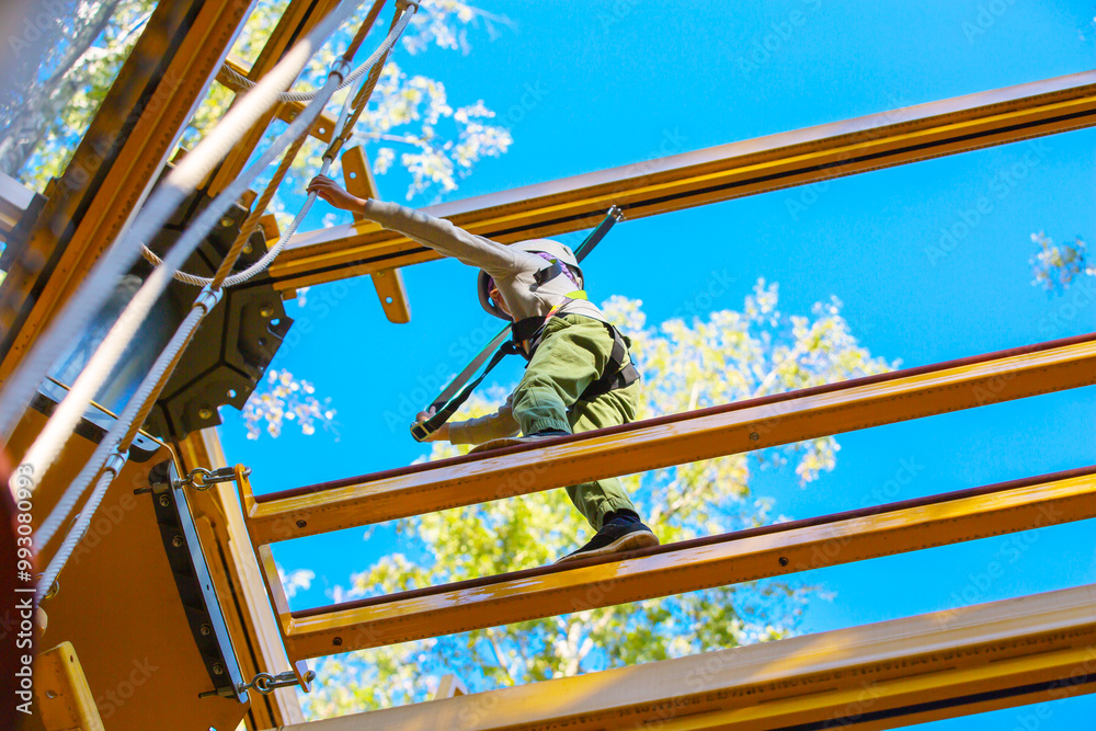 brave little boy in helmet climbing at adventure park in autumn season. Work out concept brave little boy in helmet climbing at adventure park in autumn season. Work out concept