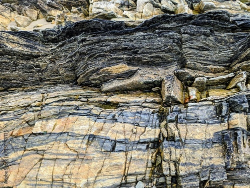Texture of the surface of compressed layered cracked rock with black and gold color bands