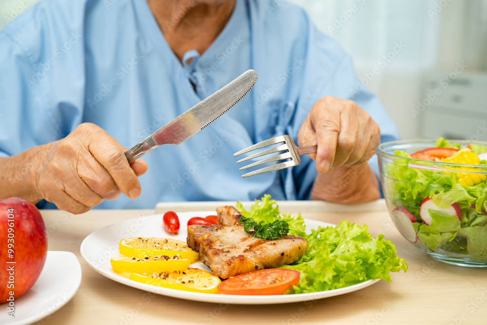 Asian elderly woman patient eating salmon stake and vegetable salad for healthy food in hospital. Asian elderly woman patient eating salmon stake and vegetable salad for healthy food in hospital.