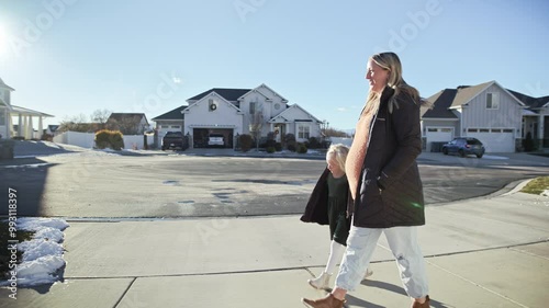 Pregnant mother walks with child in serene suburban neighborhood during winter
