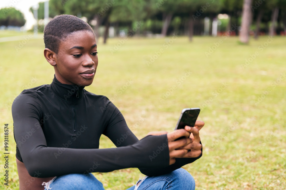 young african american young woman in casual apparel smiling happy using mobile phone in a park, concept of technology of communication and young lifestyle young african american young woman in casual apparel smiling happy using mobile phone in a park, concept of technology of communication and young lifestyle