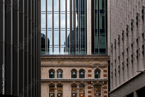 A historical building with ornate windows sits harmoniously between sleek, modern skyscrapers with reflective glass panels, symbolizing the blend of old and new architecture.