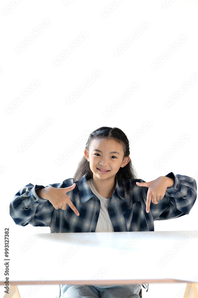 机の上で指を指す小学生の女の子