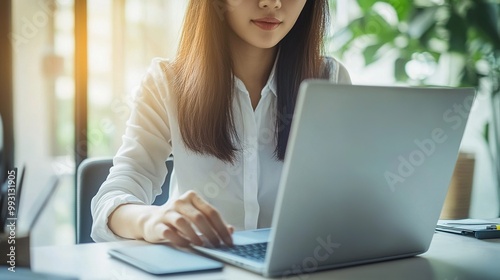 A focused woman works on her laptop in a well-lit, green setting, embodying productivity and modern workspace aesthetics.