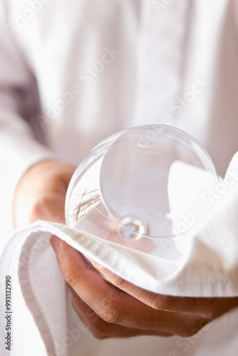Close up of a waiter's hands polishing a wine glass with a napkin
