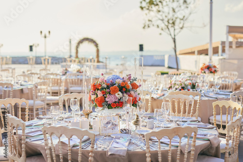 Obraz na płótnie Elegant Waterfront Outdoor Wedding Reception with Draped Canopy, Floral Centerpieces, and White Chairs at a Luxurious Seaside Venue w salonie