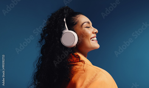 Woman enjoying music with headphones in vibrant colorblocking monochromatic set photo
