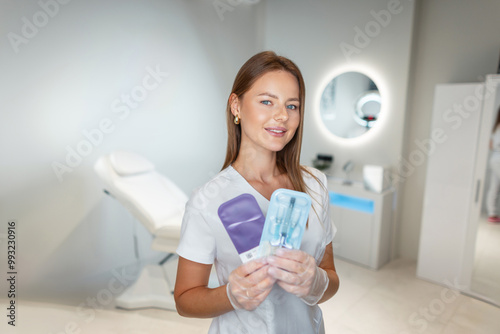 Beautiful young fresh woman doctor cosmetologist with a smile in a white coat holds filler injections and begins procedures in a beauty and health clinic photo