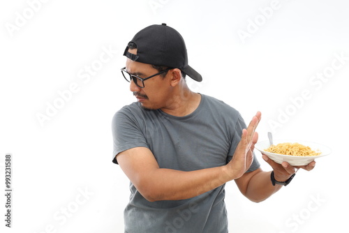 Asian Man turning away and don't want to look on fast food noodles. Refusal Harmful. Hand stop gesture. Expression. Meal photo