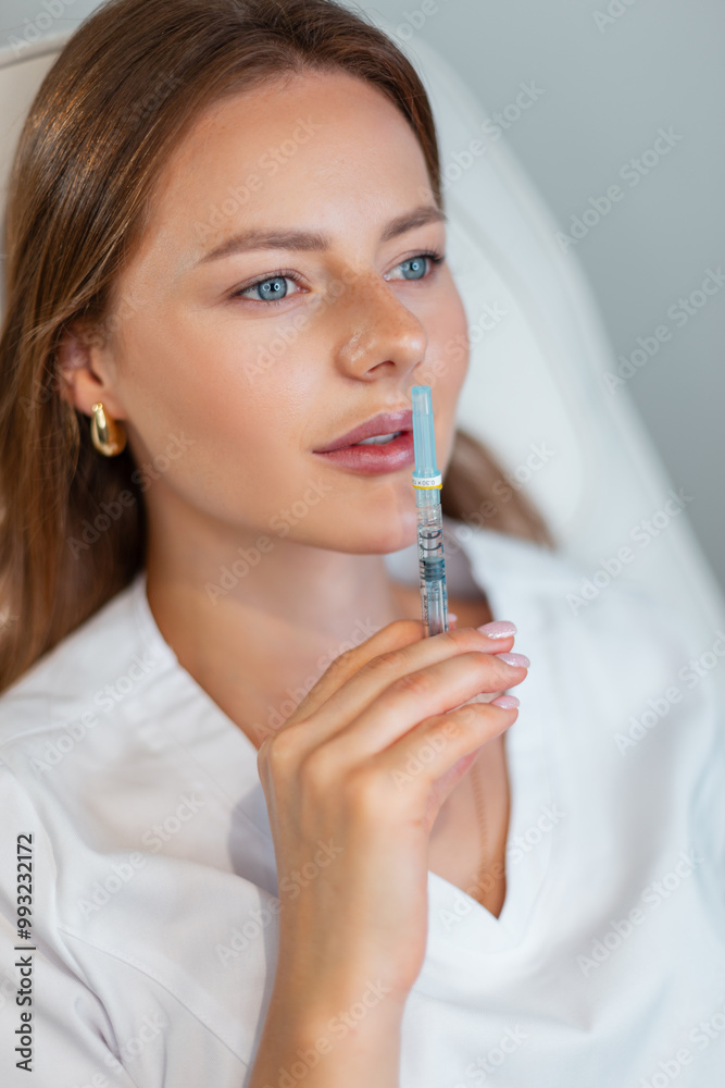 Beautiful woman cosmetologist doctor lying and holding filler injection near lips in medical clinic Beautiful woman cosmetologist doctor lying and holding filler injection near lips in medical clinic