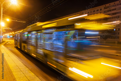 A blurred bus moves along the avenue in the evening. Shot with a long exposure.