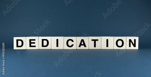 Wooden blocks spelling out DEDICATION, symbolizing unwavering commitment to a goal or purpose photo