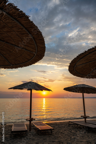 A wooden or plastic beach bed covering wooden reeds. In the background you can see the sea and a beautiful sunset.