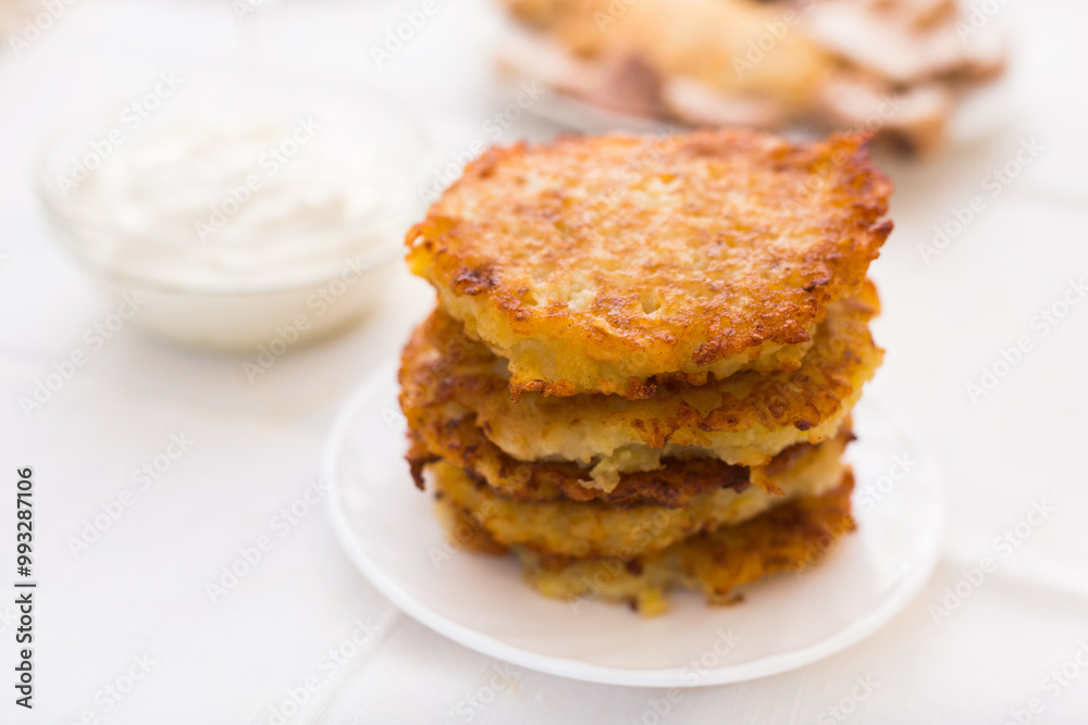 Potato pancakes with sour cream on white plate Potato pancakes with sour cream on white plate