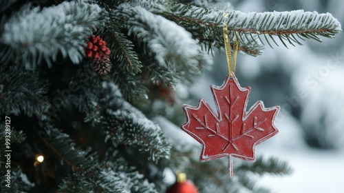 red maple leaf ornament hanging on a snowy christmas tree, representing a canadian holiday concept and the spirit of winter celebration photo