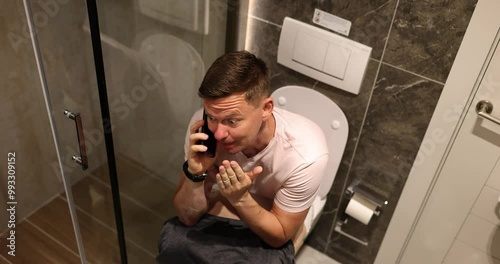 Man talks on phone telling about situation secretly hiding in toilet premise of apartment. Concept of unexpected call and uncomfortable position slow motion