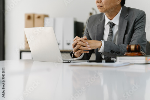 Lawyer Reviewing Case Files: A contemplative lawyer sits at his desk, reviewing case files on his laptop. The gavel and legal documents subtly hint at the seriousness of his work.