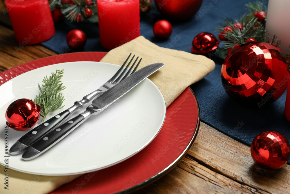Christmas place setting with plates, cutlery and festive decor on wooden table, closeup Christmas place setting with plates, cutlery and festive decor on wooden table, closeup
