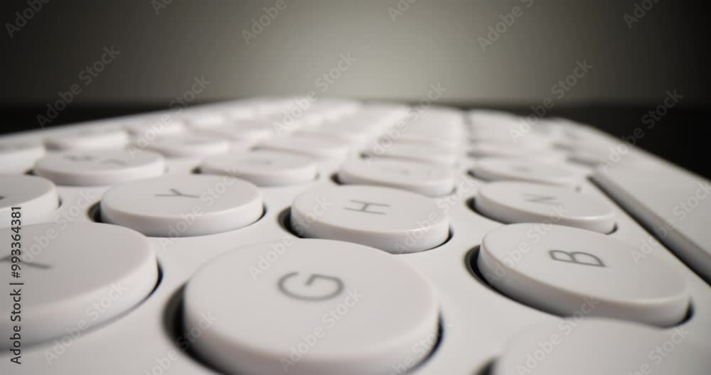 Light modern keyboard with round keys on black surface. Small neat keyboard for typing long texts and working stands under mild light in studio Light modern keyboard with round keys on black surface. Small neat keyboard for typing long texts and working stands under mild light in studio