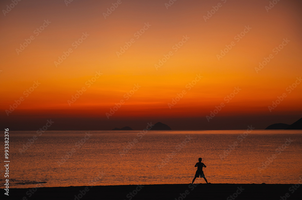 silhouette of an Asian man doing exercises on the beach by the sea in the morning at sunrise in summer silhouette of an Asian man doing exercises on the beach by the sea in the morning at sunrise in summer