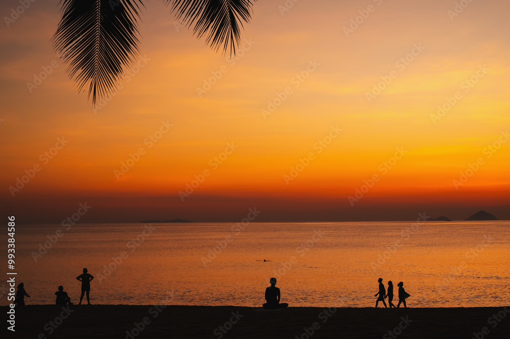 silhouettes of people relaxing on beach by sea in the morning at sunrise in summer silhouettes of people relaxing on beach by sea in the morning at sunrise in summer