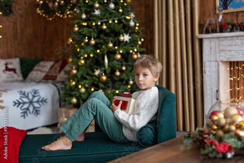 Sweet blond child, cute boy, playing with christmas toys on Christmas, beautifully decorated home for Christmas, cosy place photo