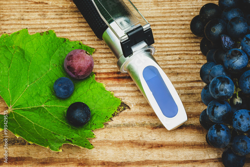 refractometer for measuring the amount of sugar and alcohol content, and grapes on a wooden table (Brix refractometer) photo