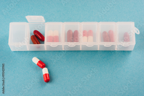 plastic organizer pill box for the week white color isolated on a blue background.