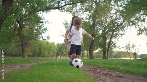 little children are playing football. people parks and nature concept. beautiful boy and girl playing with a lifestyle soccer ball in nature, running on the grass and laughing