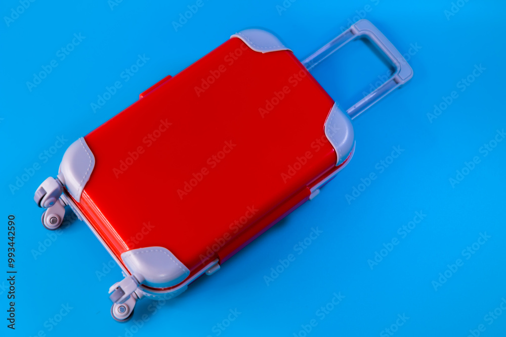 Miniature red suitcase top view on a blue background, travel luggage concept Miniature red suitcase top view on a blue background, travel luggage concept
