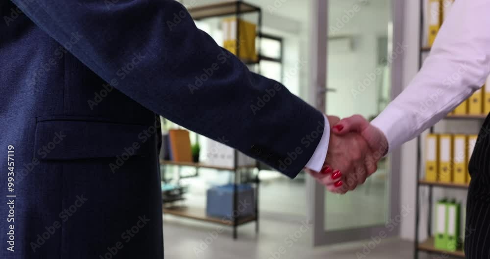 Businessman shakes hands of partner at meeting in company office slow motion. Colleague greets female employee with handshake gesture