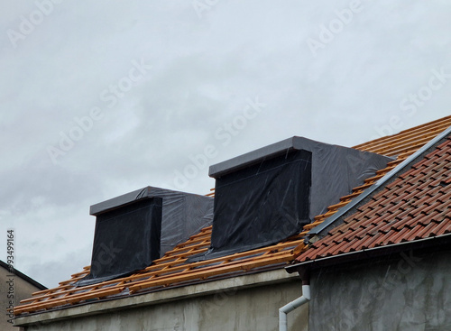 bay windows newly inserted into the roof during the renovation. two projections covered with vapor barrier film towards the street.