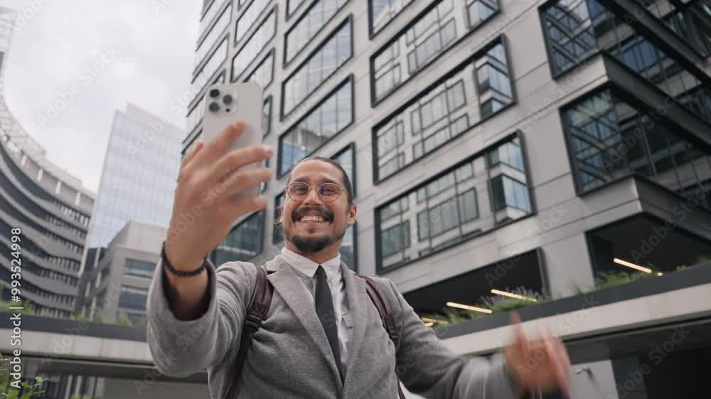 Happy Caucasian male holding smartphone in front of his face. Fixing hair with one hand. Waving to camera while talking with video call. Remote communication concept. Speaking with relatives. Happy Caucasian male holding smartphone in front of his face. Fixing hair with one hand. Waving to camera while talking with video call. Remote communication concept. Speaking with relatives.