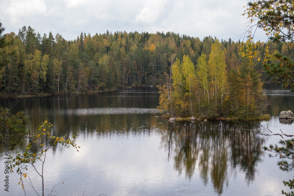 A nordic lake with a small island in the middle during early fall season. A nordic lake with a small island in the middle during early fall season.