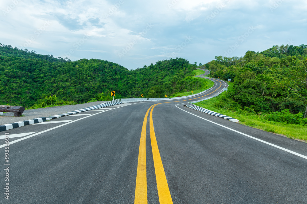 Long curvy forest asphalt road over the hills. Beautiful curved road in the forest. Side view of road Long curvy forest asphalt road over the hills. Beautiful curved road in the forest. Side view of road