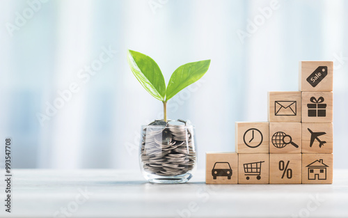 Glass jar filled with coins sits beside a stack of wooden blocks, each marked with various symbols. This arrangement represents the concepts of savings, investment, and financial strategy