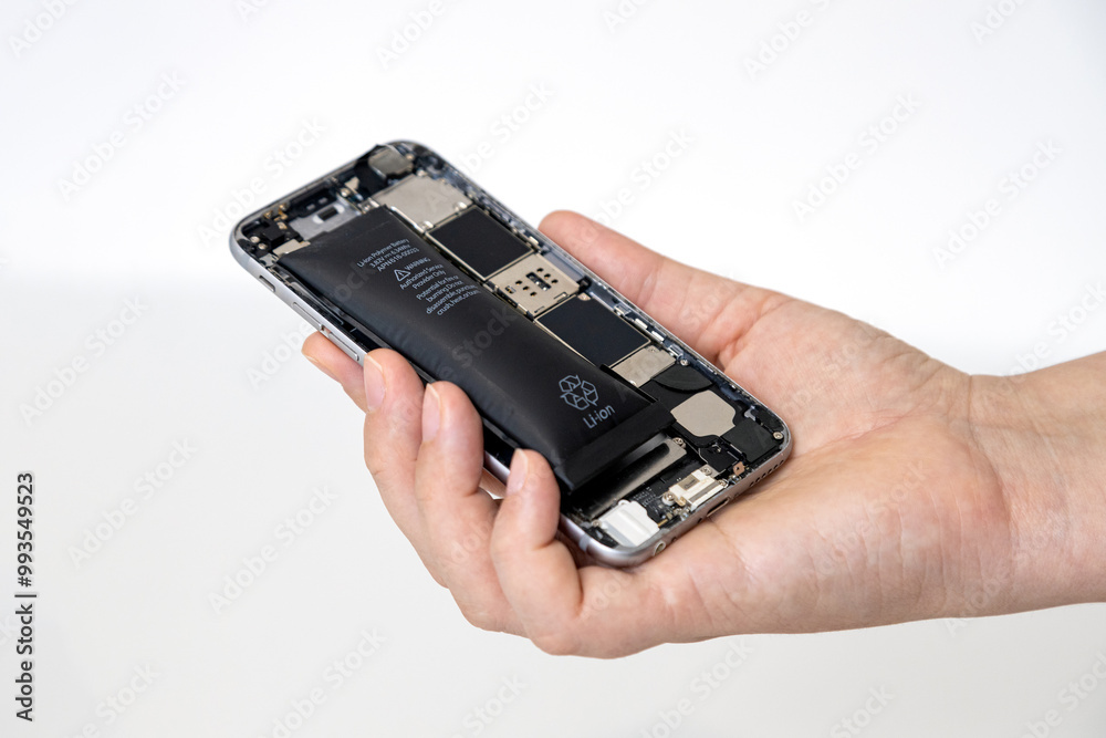 Hand holding a disassembled phone with a swollen battery against a white background Hand holding a disassembled phone with a swollen battery against a white background