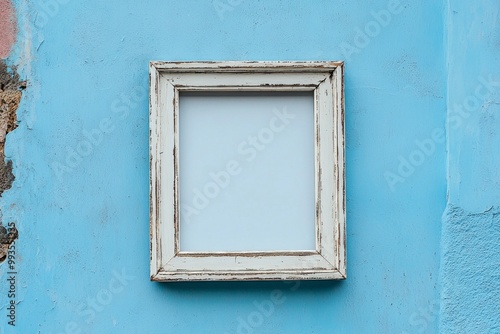 A pale blue wall with a whitewashed wooden frame, the blank center blending gently into the background 