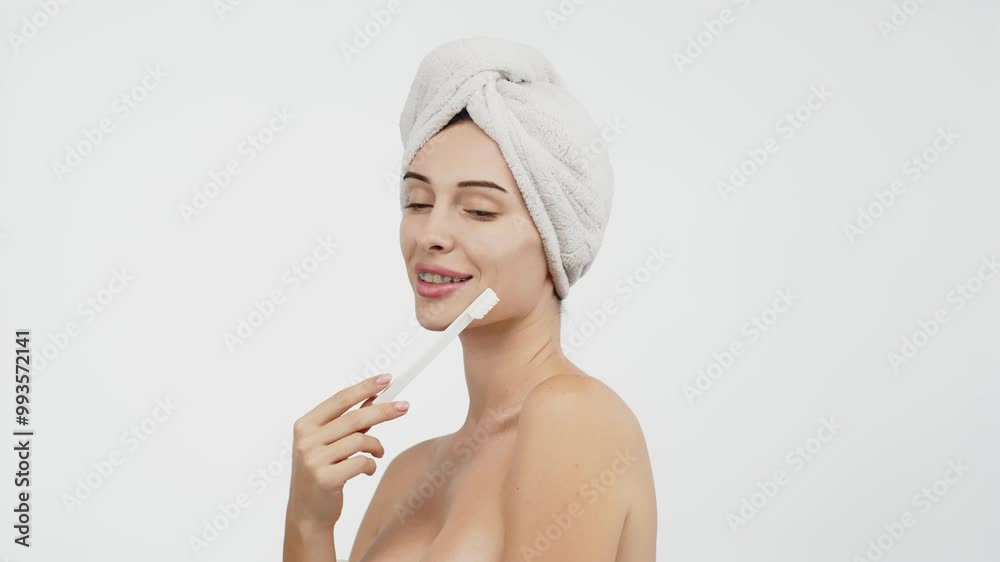 The concept of beauty and personal hygiene. An attractive, happy young woman in a bath towel holds a toothbrush. This image embodies self-care and the joy of daily routines. The concept of beauty and personal hygiene. An attractive, happy young woman in a bath towel holds a toothbrush. This image embodies self-care and the joy of daily routines.