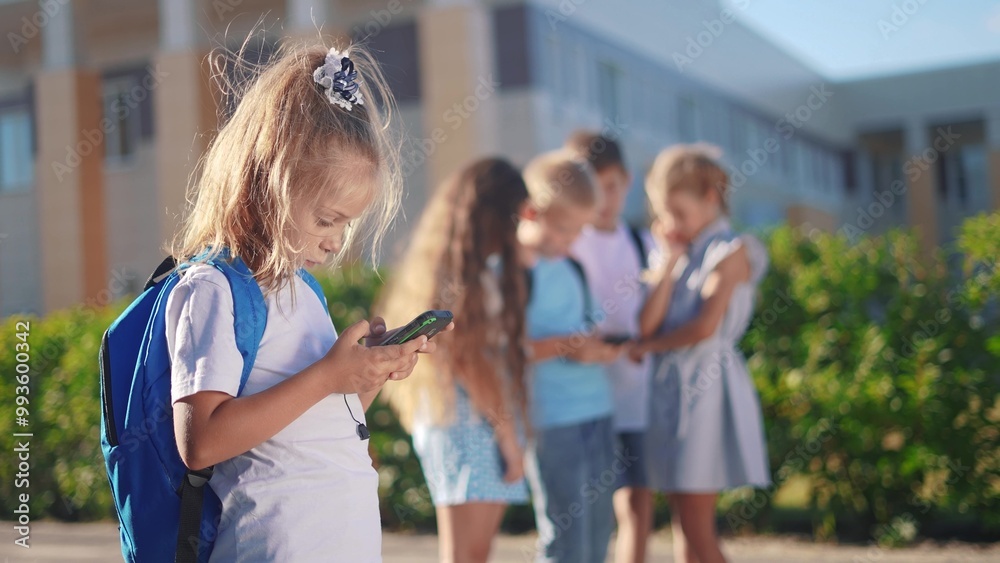 Obraz premium pupils stand in the schoolyard and look at phones. business concept of modern lifestyle training and development. a group of students lifestyle playing on the phone in the backyard of the school