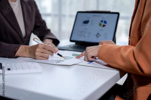 Business team working together on a new project with graphs and using a laptop at the office